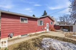 The property features red horizontal siding and a white side door, with a paved area leading to an uncovered patio - 