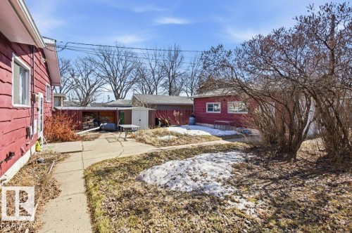 The property features a red exterior, a concrete pathway, and a detached red outbuilding with windows - 10459 66 Avenue, Edmonton, AB - Outdoor