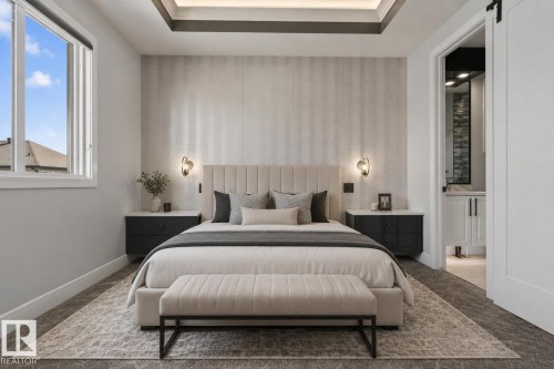 Spacious bedroom featuring textured accent wall, tray ceiling with recessed lighting, and wall-mounted sconces - 707 180 Street, Edmonton, AB - Indoor Photo Showing Bedroom