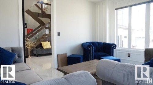 Living area featuring light-colored walls, large windows, and white tile flooring - 707 180 Street, Edmonton, AB - Indoor