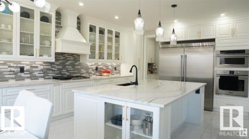 The kitchen features white cabinetry, a large central island with a white countertop, and stainless steel appliances - 707 180 Street, Edmonton, AB - Indoor Photo Showing Kitchen With Upgraded Kitchen