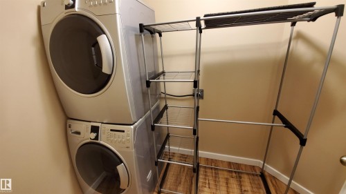 Dedicated laundry area featuring a stacked washer and dryer, along with wood-style flooring - 2103 1601 8 Avenue, Cold Lake, AB - Indoor Photo Showing Laundry Room
