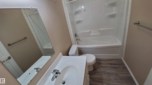 Bathroom featuring a white vanity with an integrated sink, a mirror, and a bathtub with a shower - 2103 1601 8 Avenue, Cold Lake, AB - Indoor Photo Showing Bathroom