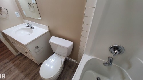 Bathroom featuring a vanity with a white countertop and an integrated sink, a commode, and a bathtub with chrome fixtures - 2103 1601 8 Avenue, Cold Lake, AB - Indoor Photo Showing Bathroom