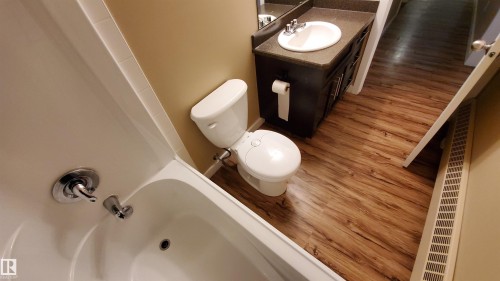 The bathroom features a white bathtub with chrome fixtures, a white toilet, and a dark wood vanity with a white sink - 2103 1601 8 Avenue, Cold Lake, AB - Indoor Photo Showing Bathroom