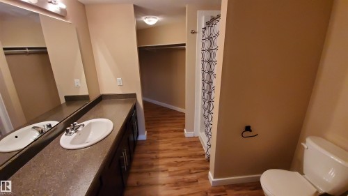 The bathroom features a dual sink vanity with ample countertop space, a toilet, and a shower with a patterned curtain - 2103 1601 8 Avenue, Cold Lake, AB - Indoor Photo Showing Bathroom
