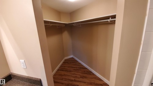 The property features a closet with shelving and a hanging rod, set against light-colored walls and wood-look flooring - 2103 1601 8 Avenue, Cold Lake, AB - Indoor With Storage