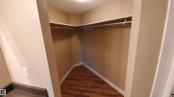The property features a closet with shelving and a hanging rod, set against light-colored walls and wood-look flooring - 