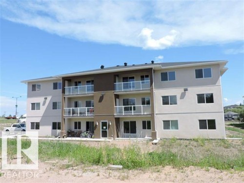 The property features a three-story building with a light-colored exterior and dark trim accents - 2103 1601 8 Avenue, Cold Lake, AB - Outdoor