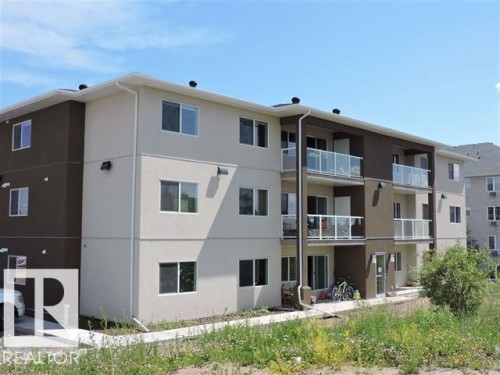 This property features a modern exterior with a mix of light and dark facade panels, white window frames, and balconies with glass railings - 2103 1601 8 Avenue, Cold Lake, AB - Outdoor