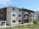 This property features a modern exterior with a mix of light and dark facade panels, white window frames, and balconies with glass railings - 2103 1601 8 Avenue, Cold Lake, AB  - Outdoor 