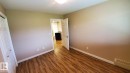 The room features wood-look flooring, light-colored walls, and white baseboards - 2103 1601 8 Avenue, Cold Lake, AB  - Indoor Photo Showing Other Room 