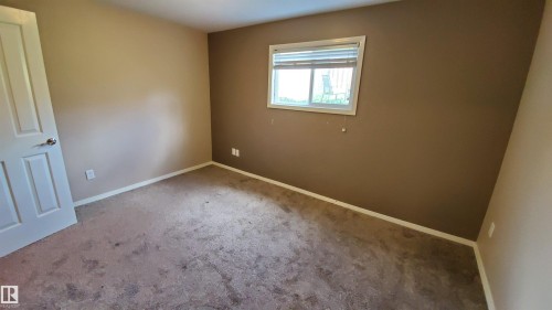 A cozy room with neutral-toned walls, carpeted flooring, and a window providing natural light - 2103 1601 8 Avenue, Cold Lake, AB - Indoor Photo Showing Other Room