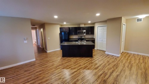Open concept kitchen with dark cabinetry, stainless steel appliances, and a central island with a sink - 2103 1601 8 Avenue, Cold Lake, AB - Indoor