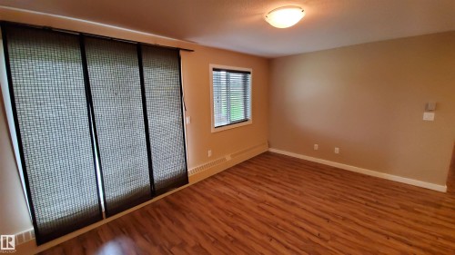This room features rich wood-look flooring, neutral wall tones, and a window with blinds - 2103 1601 8 Avenue, Cold Lake, AB - Indoor Photo Showing Other Room