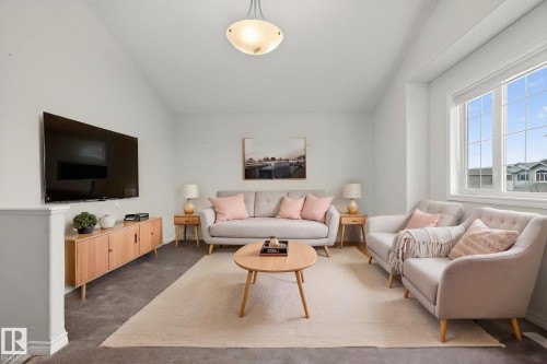 The property features a bright living area with a large window, providing natural light, carpeted flooring, and a contemporary ceiling light fixture - 96 Dalquist Bay, Leduc, AB - Indoor Photo Showing Living Room