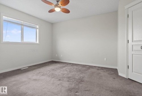 This room features neutral-toned walls and carpet, a window with horizontal blinds, and a ceiling fan with wooden blades - 96 Dalquist Bay, Leduc, AB - Indoor Photo Showing Other Room