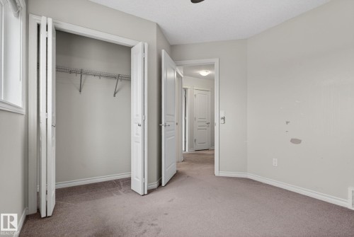 This room features soft gray carpeting, a window providing natural light, and a closet with bi-fold doors and wire shelving - 96 Dalquist Bay, Leduc, AB - Indoor Photo Showing Other Room