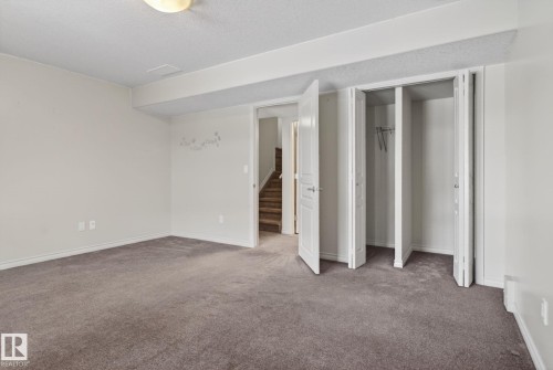 Carpeted room featuring a ceiling light fixture, bi-fold closet doors, and access to a stairwell - 96 Dalquist Bay, Leduc, AB - Indoor Photo Showing Other Room