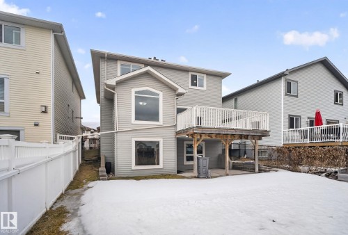 The property features a rear exterior with light gray siding, a white fenced perimeter, and a raised wooden deck with white railings - 96 Dalquist Bay, Leduc, AB - Outdoor With Exterior