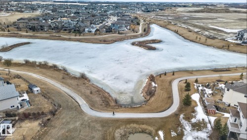 Aerial view showcasing the community with a frozen body of water, surrounding walking paths, and residential properties - 96 Dalquist Bay, Leduc, AB - Outdoor With View
