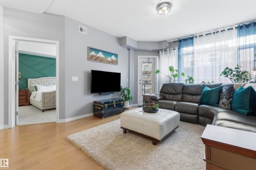 The living area features light wood flooring, a light-colored area rug, and an exterior door with glass panels - 316 141 Festival Way, Sherwood Park, AB - Indoor Photo Showing Living Room