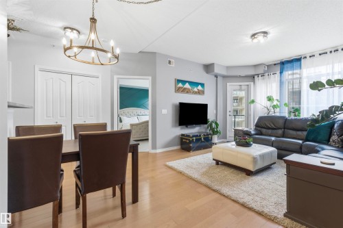 Open concept living space featuring light hardwood flooring, a dining area with a chandelier, and a living area with a large window and access to an outdoor space - 316 141 Festival Way, Sherwood Park, AB - Indoor Photo Showing Living Room