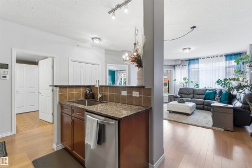 The property features wood flooring, a kitchen area with a stainless steel sink, and a living area with large windows - 316 141 Festival Way, Sherwood Park, AB - Indoor