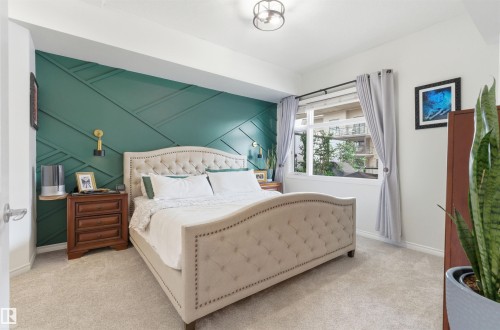 This room features a decorative accent wall with geometric paneling, a tufted bed frame, and carpeted floors - 316 141 Festival Way, Sherwood Park, AB - Indoor Photo Showing Bedroom