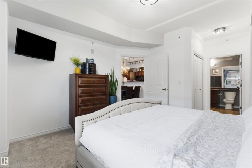 This property features a bedroom with neutral carpeting and a bed with a tufted headboard - 316 141 Festival Way, Sherwood Park, AB - Indoor Photo Showing Bedroom