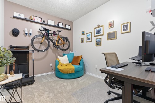 This versatile room features neutral-toned carpet flooring, a desk area with an office chair, and a decorative wall shelf - 316 141 Festival Way, Sherwood Park, AB - Indoor Photo Showing Office