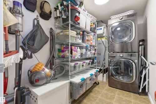 Utility room featuring a stacked washer and dryer, tile flooring, and wire shelving for storage - 316 141 Festival Way, Sherwood Park, AB - Indoor Photo Showing Laundry Room