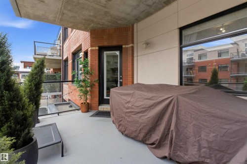 The property features a private balcony with a concrete floor, glass and metal railings, and a brick exterior wall - 316 141 Festival Way, Sherwood Park, AB - Outdoor