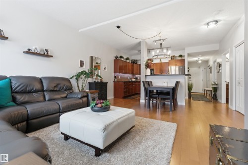 Open concept living area featuring light hardwood flooring, a dining area, and a kitchen with wooden cabinetry and stainless steel appliances - 316 141 Festival Way, Sherwood Park, AB - Indoor Photo Showing Living Room
