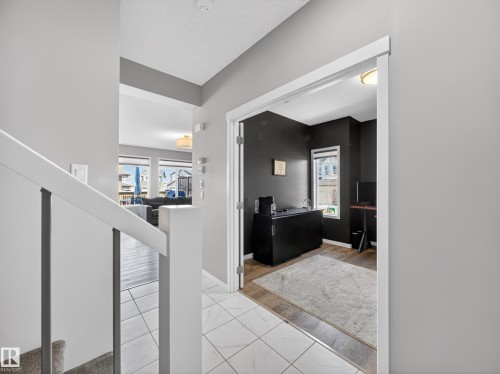 The property features a spacious entryway with tile flooring, leading to a room with dark walls and a window - 3210 Chernowski Way, Edmonton, AB - Indoor Photo Showing Other Room