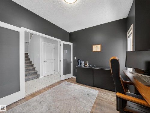 This room features wood plank flooring and dark walls, with white trim around the doorways - 3210 Chernowski Way, Edmonton, AB - Indoor Photo Showing Office