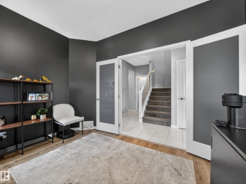 This room features dark walls, hardwood style flooring, and a light-colored area rug - 3210 Chernowski Way, Edmonton, AB - Indoor Photo Showing Other Room