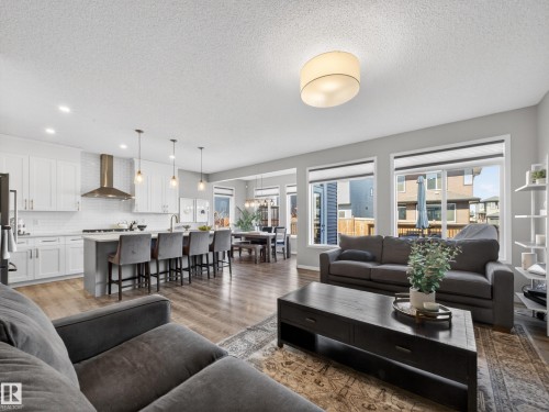 The open concept living area features light-colored walls, recessed lighting, and large windows, providing abundant natural light - 3210 Chernowski Way, Edmonton, AB - Indoor Photo Showing Living Room