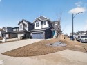 The property features a two-story exterior with dark siding and white trim, an attached garage, and a light blue front door - 3210 Chernowski Way, Edmonton, AB  - Outdoor With Facade 