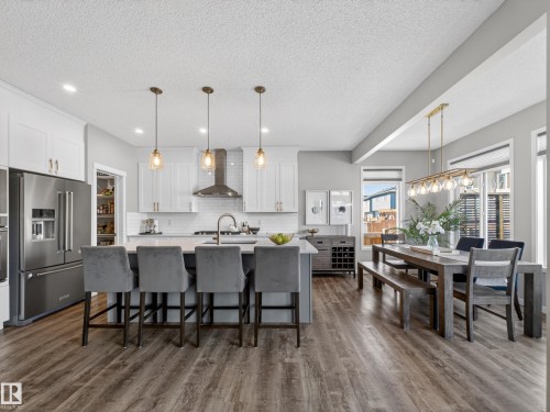 This property features an open concept kitchen and dining area with wood-look flooring - 3210 Chernowski Way, Edmonton, AB - Indoor Photo Showing Kitchen With Stainless Steel Kitchen With Upgraded Kitchen