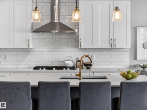The kitchen features white shaker-style cabinetry, a white subway tile backsplash, and a stainless steel range hood - 3210 Chernowski Way, Edmonton, AB - Indoor Photo Showing Kitchen With Upgraded Kitchen
