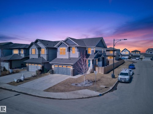 The property features a dark gray exterior with light gray trim, a light blue front door, and an attached two-car garage - 3210 Chernowski Way, Edmonton, AB - Outdoor With Facade