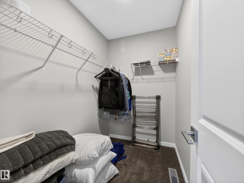 This closet features carpet flooring, wire shelving, and a modern door handle - 3210 Chernowski Way, Edmonton, AB - Indoor Photo Showing Other Room