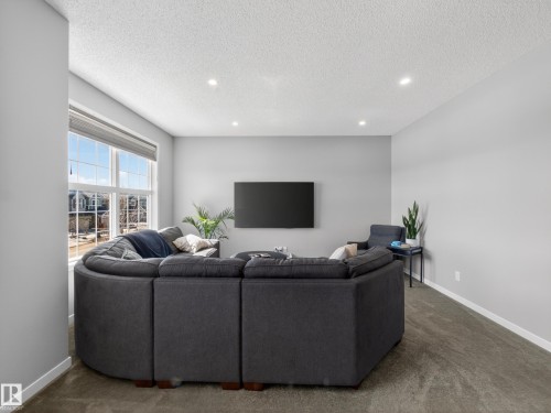 Living room featuring recessed lighting, a large window providing natural light, and carpeting - 3210 Chernowski Way, Edmonton, AB - Indoor