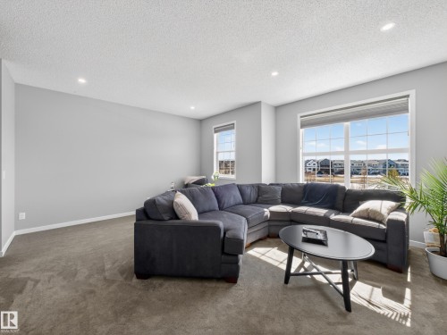 Living area with neutral-toned carpet, light gray walls, and large windows offering exterior views - 3210 Chernowski Way, Edmonton, AB - Indoor Photo Showing Living Room