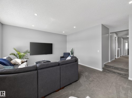Spacious living area featuring light gray walls, recessed lighting, and soft gray carpeting - 3210 Chernowski Way, Edmonton, AB - Indoor