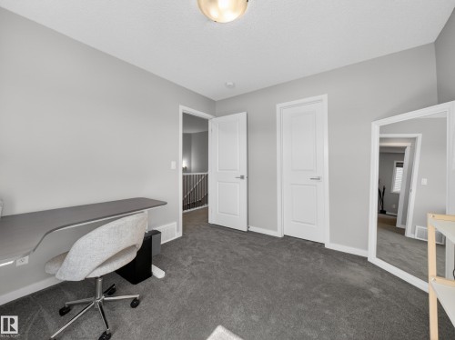 This room features light grey walls and dark grey carpeting, providing a neutral aesthetic - 3210 Chernowski Way, Edmonton, AB - Indoor