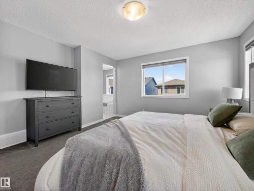 The property features light gray walls, carpeted flooring, and a window providing natural light - 3210 Chernowski Way, Edmonton, AB - Indoor Photo Showing Bedroom