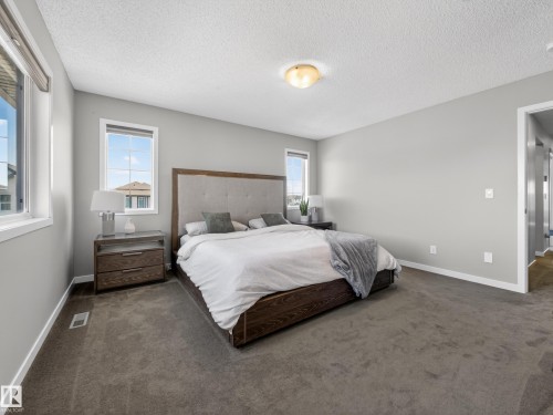 This spacious room features gray carpeting and light gray walls, creating a neutral and inviting atmosphere - 3210 Chernowski Way, Edmonton, AB - Indoor Photo Showing Bedroom