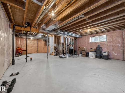 Spacious unfinished basement with exposed wooden joists, a window, and insulated walls - 3210 Chernowski Way, Edmonton, AB - Indoor Photo Showing Basement